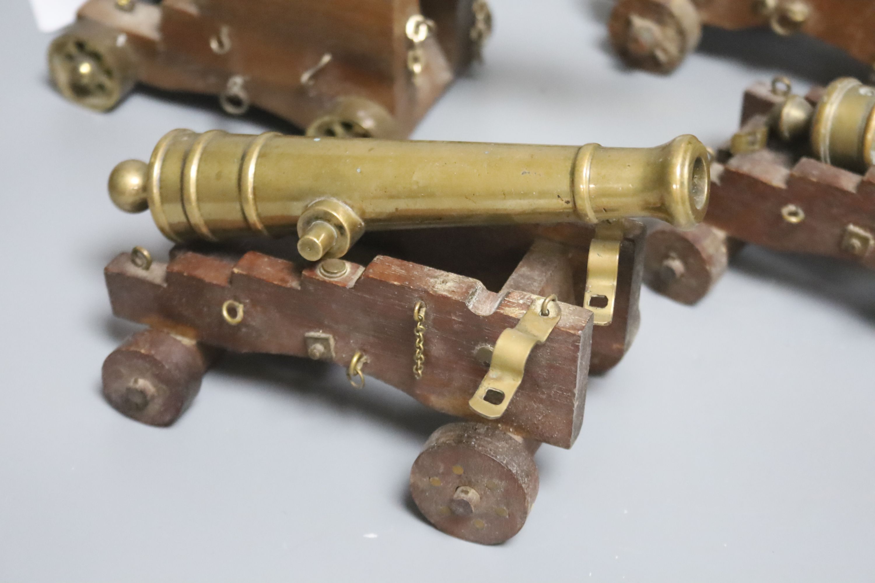 Four bronze or brass model cannons, with associated wood carriages, 20th century, barrel lengths 18-24.5cm